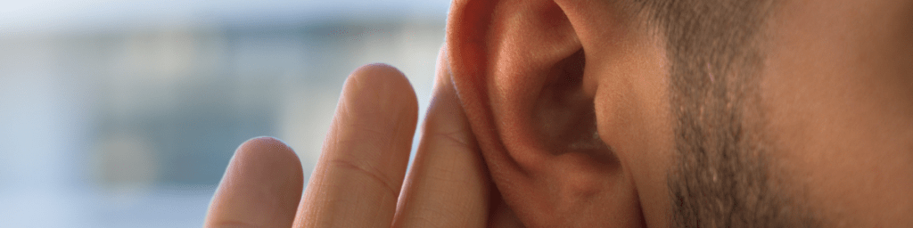 Man holding his hand to his ear to hear better. 