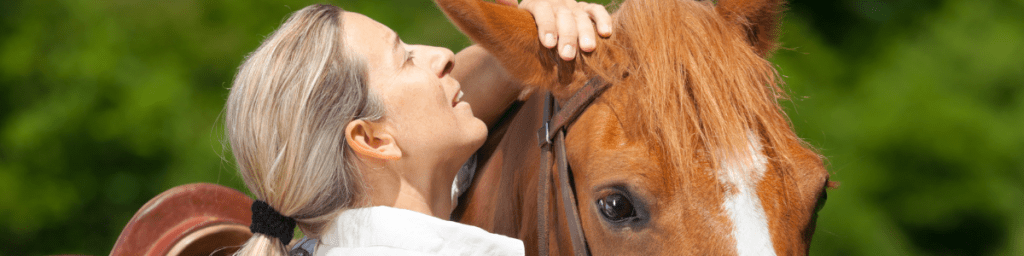 Woman whispering into a horse's ear.
